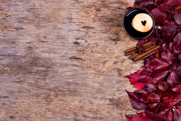 Hot Mulled wine with spices and fruits on an old wooden background. Autumn leaves, nuts, cinnamon. Autumn background. Text space.