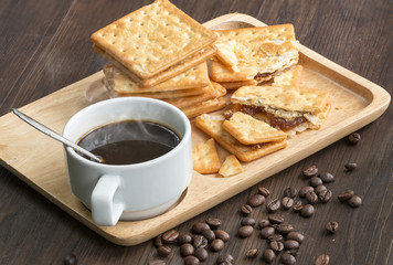 Black coffee,cracker and coffee bean on wood with warm morning light.Copy space.