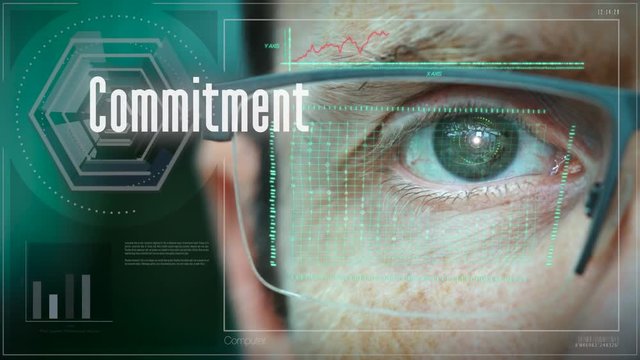 A close up of a businessman eye controlling a futuristic computer system with an Commitment concept.