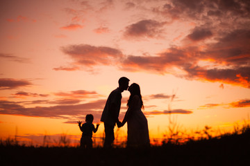 Fototapeta na wymiar family, silhouettes of mom and dad on a background of beautiful sky, sunset, family at sunset