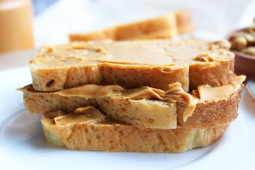 toasted white bread smeared peanut butter on a white plate on a light background