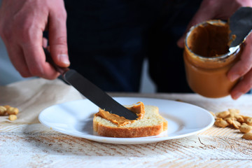 Obraz na płótnie Canvas toasted white bread smeared peanut butter on a white plate on a light background