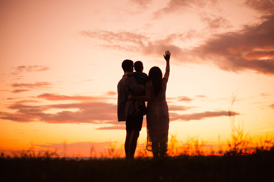 family, silhouettes of mom and dad on a background of beautiful sky, sunset, family at sunset