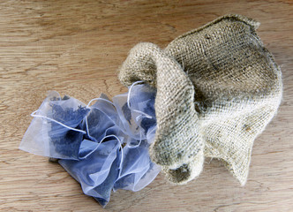 bags of elite tea in silk fabric packing in a canvas bag on a wooden background..