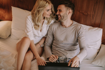 Loving couple surfing on internet on the bed in bedroom