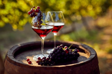 Twee glazen rode wijn met een fles op een houten vat
