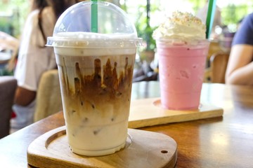 In the cafe, iced coffee with ice cubes in a cup on wooden background