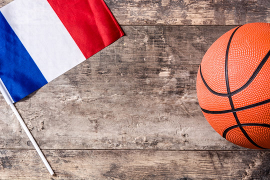 Basketball and French flag on wooden table. Top view.