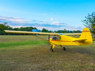 yellow airplane startup engine and prepare for takeoff on grass airfield