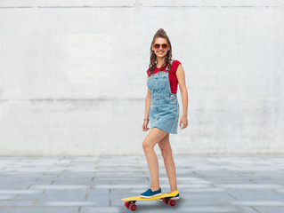 sport, leisure and skateboarding concept - smiling teenage girl with short modern cruiser...