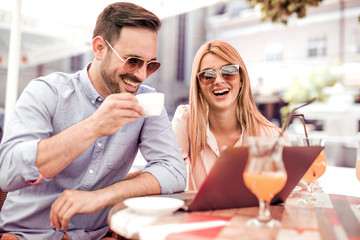 Happy friends meeting at cafe with laptop.