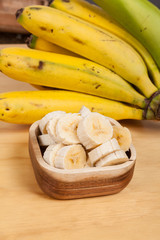 chopped banana in wooden bowl, on wooden background