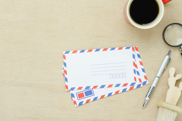 Table top view aerial image of business office desk background concept.Flat lay object ongoing write envelope by pen with black coffee on modern rustic brown wooden.Copy space for creative design text