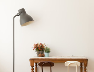 Black lamp with vase of flower on desk in modern room on white background.