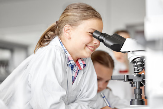 education, science and children concept - kids or students with microscope studying biology at school laboratory - Powered by Adobe