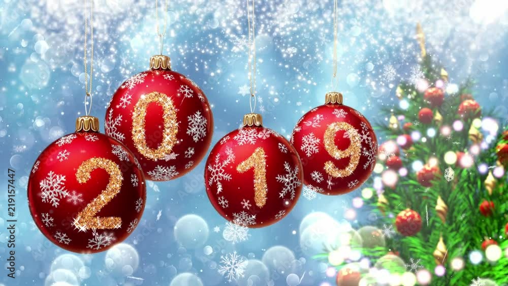 Wall mural red balls with numbers 2019 hanging on the background of a blue bokeh and a rotating christmas tree 