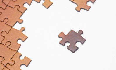 Concept image of one piece missing on a puzzle on a white surface.