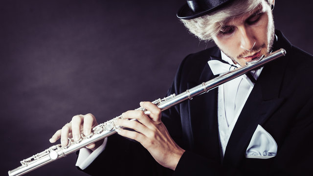 Elegantly dressed male musician playing flute