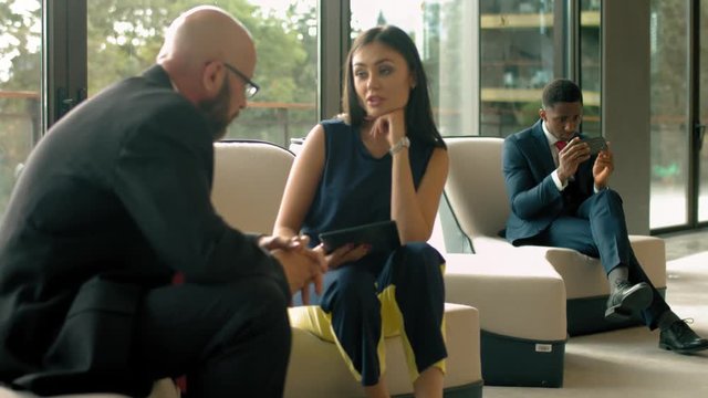 Mature businessman discuss information with a younger colleague in a modern business lounge