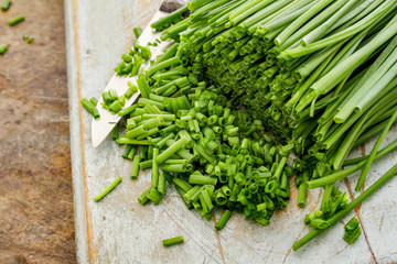 slicing fresh chives on chopping board