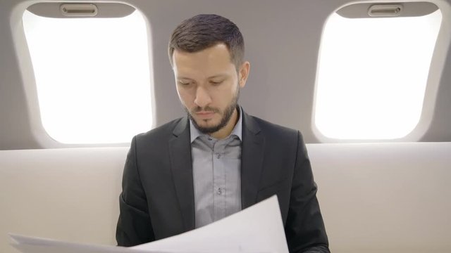 Portrait of young lawyer businessman sitting on sofa in private entrepreneur plane and readng reports