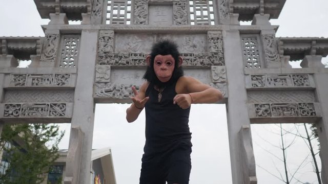 Adult man acting silly funny in monkey mask in front of ancient temple somewhere in asia
