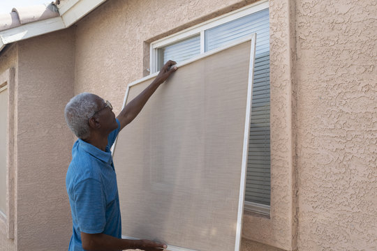 Senior Man Installing A Window Screen.