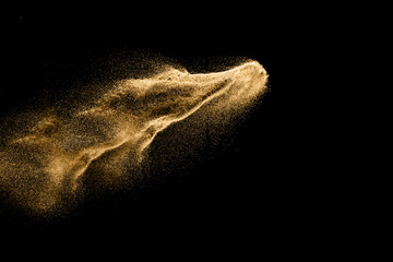 Dry river sand explosion. Golden colored sand splash agianst dark background.