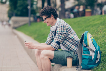 Obraz premium Curly haired cute attractive smiling handsome guy with smartphon