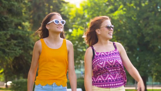 leisure and friendship concept - happy smiling teenage girls or friends walking in summer park