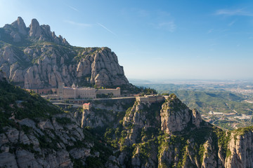 Panoramic aerial view of Santa Maria de Montserrat Abbey, stone mountain monastery from opposite side of mountain in Montserrat, Barcelona, Spain