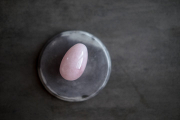 Rose quartz crystal vaginal yoni egg on dark background. Copy space