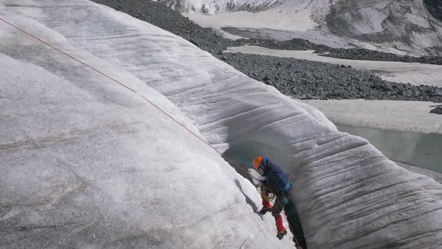 Mountaineer Man in Crampons is Using Ascender on Fixed Rope on Steep Slope in Mountains. Slow Motion
