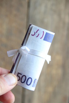 hand holds five hundred euros with ribbon, priz and winnings