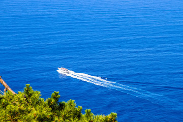 Aerial view of a boat cruising on the blue Mediterranean sea on a sunny day.