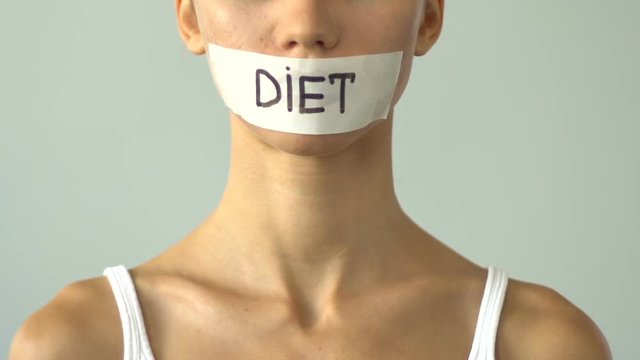 Diet written on taped mouth of slim girl, severe self-restrictions, anorexia