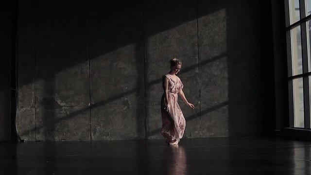 a young beautiful ballerina in pointe shoes and a long fluttering dress elegantly moves and dances. slow motion
