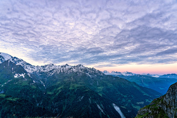 Scenic view of beautiful landscape in Swiss Alps. Fresh green meadows and snow-capped mountain tops in the background in springtime, Switzerland.