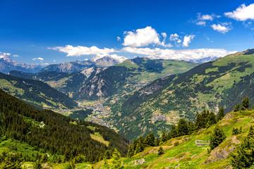 Naklejka na ściany i meble Scenic view of beautiful landscape in Swiss Alps. Fresh green meadows and snow-capped mountain tops in the background in springtime, Switzerland.