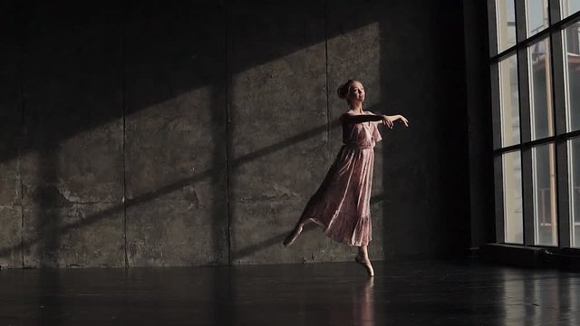 elegant ballerina in a long fluttering dress pointes dancing against a dark background in the studio