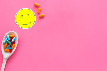 Reception of medicines concept. Recovery. Pills in spoon near smile face emoji on pink background top view copy space