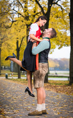 Obraz premium Southern German couple in Tracht in loving embrace, he is lifting her up