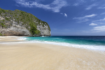 Fototapeta na wymiar Shades of blue contrasted with white sand at Kelingking Beach on Nusa Penida in Indonesia.
