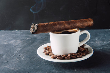 Cup of coffee, coffee beans, ashtray with cigar on dark background