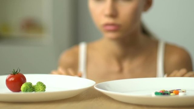Frustrated girl chooses vegetables or anti-obesity pills, healthy diet vs drugs