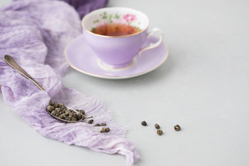 Adderley Bone China Tea Cup and Saucer with Loose Leaf Herbal Tea in Silver Spoon Beside; Grey Background