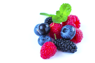 Close-up arrangement mixed, assorted berries including blackberries, strawberry, blueberry, raspberries and fresh leaf on white