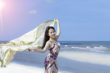 Cute yong Asian woman flights relaxing on the beach.