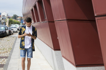 young man with mobile phone walking down the street