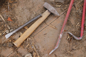 hammer, cold chisel and two wrecking bars on dirty wooden floor